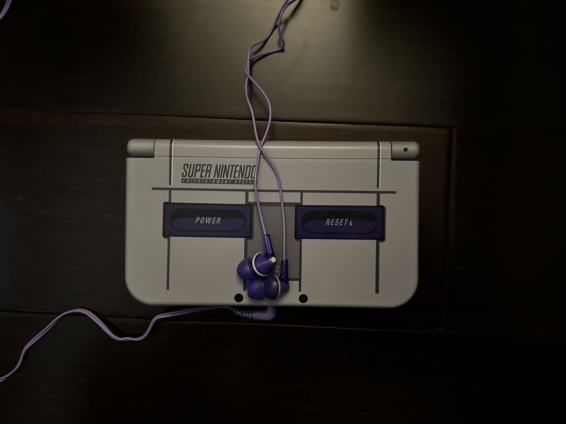 The Super Nintendo edition of the New Nintendo 3DS XL, with Panasonic earbuds.
