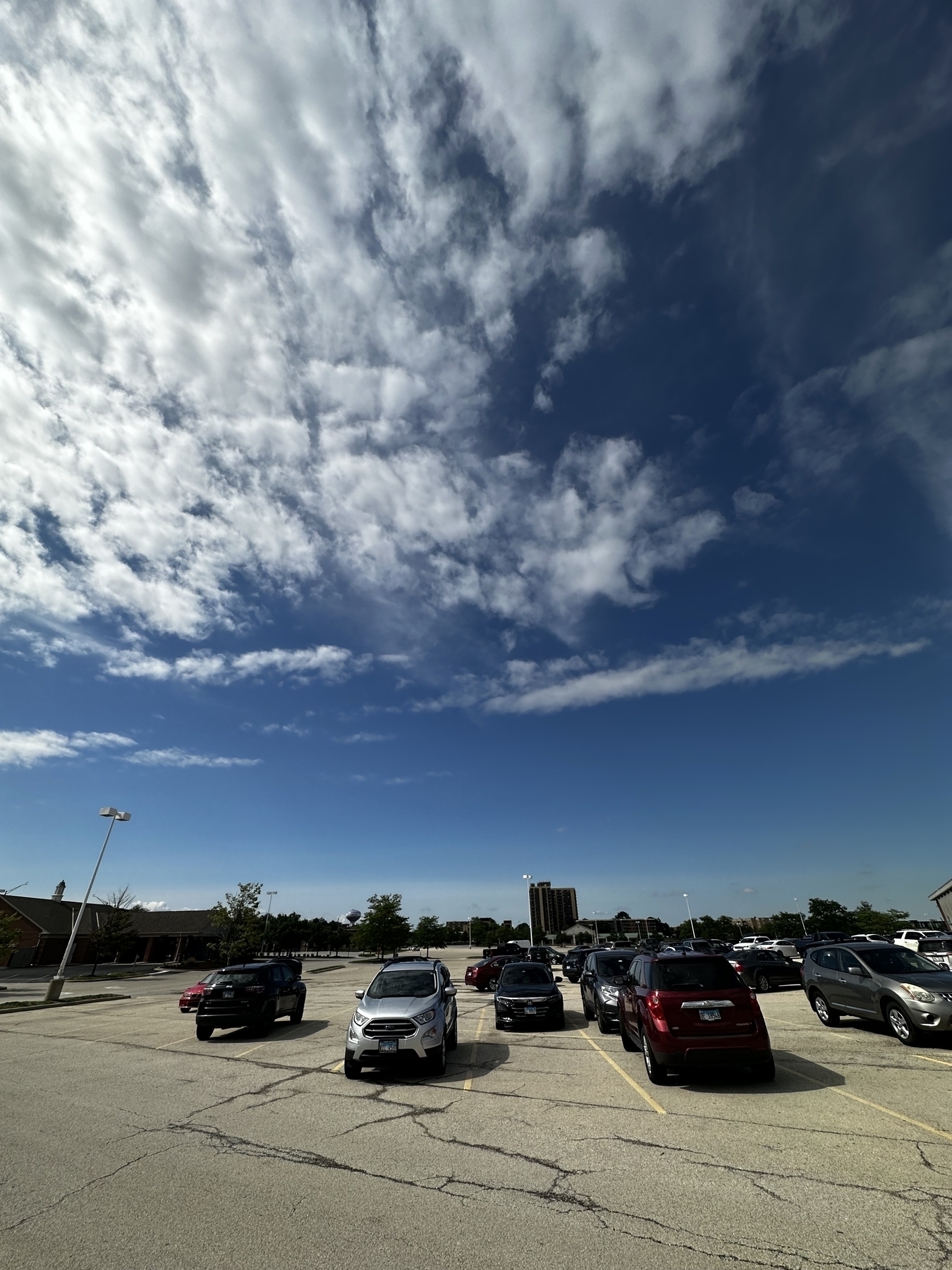 Blue sky with patchy clouds over a parking lot 